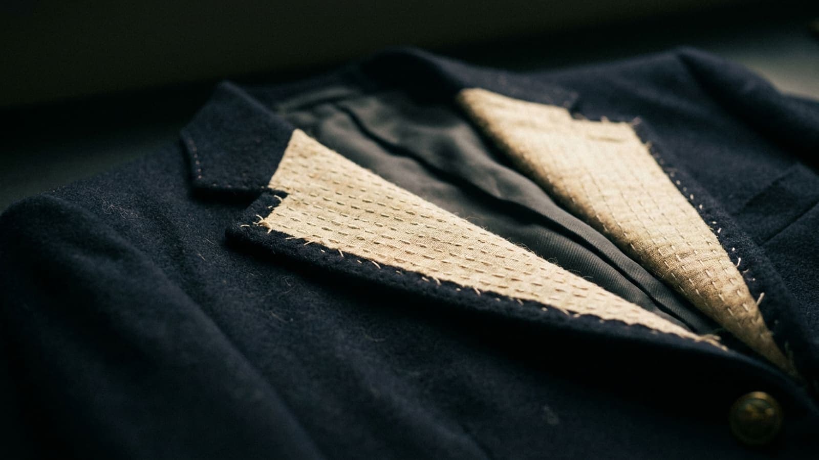 The inside of a jacket front turned back to show rows of pad stitching across the canvas
