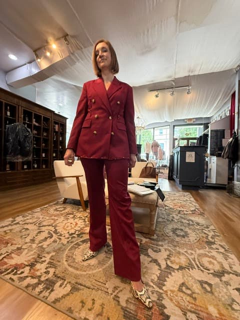 A client in a deep red double-breasted trouser suit with gold buttons, on the shopfloor