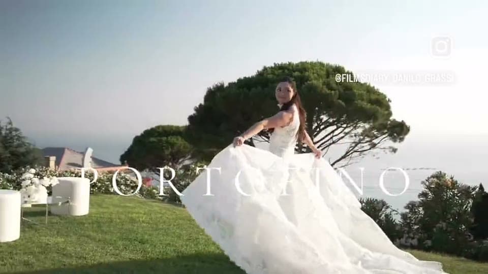 A bride holding out the train of her ivory gown on a clifftop lawn above the sea at Portofino